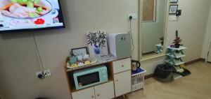 a room with a tv on a wall with a microwave at La Suite@Alanis Residence in Sepang