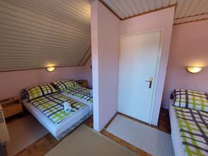 duas camas num pequeno quarto com uma porta em Alina vendégház em Mezőkövesd