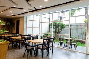 a restaurant with tables and chairs and large windows at Arcadia Hotel Manado in Manado