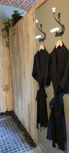 un mur avec deux robes noires accrochées au mur dans l'établissement Coeur de ferme en Pévèle, 
