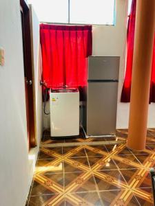 Cette chambre comprend un réfrigérateur et un rideau rouge. dans l'établissement Departamento acogedor listo para disfrutar, à Moyobamba