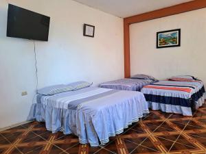 two beds in a room with a flat screen tv at Departamento acogedor listo para disfrutar in Moyobamba