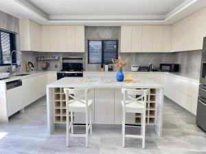 a white kitchen with a table and two stools at Penshurst Guest House in Sydney