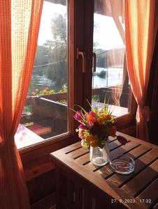 a table with flowers on it next to a window at Restoran Domaćin in Bosanski Novi
