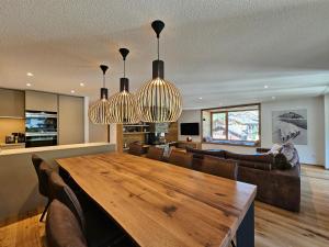 a living room with a wooden table and two chandeliers at Riverside 3rd Floor North in Saas-Fee