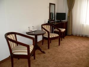 ブラショヴにあるPension Deutsches Hausの椅子3脚、テーブル、テレビが備わるお部屋
