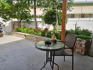 a glass table and two chairs with a bottle on it at Garden Square Inn in Markopoulo