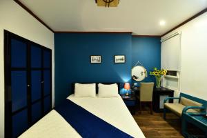 1 dormitorio con pared azul, cama y escritorio en Hanoi Starlight Boutique Hotel, en Hanói