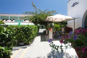 a patio with an umbrella and tables and flowers at Hotel Residence Nemo in Brindisi