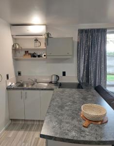 a kitchen with a counter with a sink and a table at Bethlehem Apartment in Tauranga