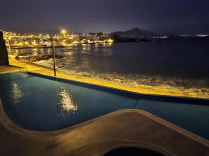 - une piscine avec vue sur l'eau la nuit dans l'établissement Departamento de Playa San Bartolo Ocean Reef - SOL, ARENA Y MAR, à San Bartolo