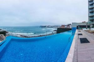 a large blue swimming pool next to the ocean at Departamento de Playa San Bartolo Ocean Reef - SOL, ARENA Y MAR in San Bartolo