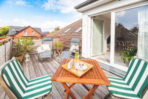 a patio with a wooden table and chairs on a balcony at Casa Ueberall in Fehmarn