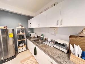 a kitchen with white cabinets and a stainless steel refrigerator at Charm’s Place in Olongapo