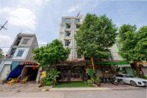 a tall white building with trees in front of it at Hanoi Airport Hotel - Convenient & Friendly in Noi Bai