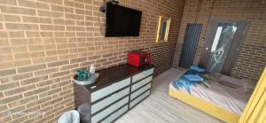 a bedroom with a bed and a tv on a brick wall at WILLA VASCO BOSMAN in Rewa +9 photos