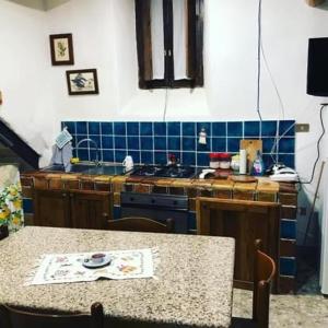 a kitchen with a table and a blue tiled wall at Casa della Luna in Tarano
