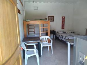 Habitación pequeña con cama, escritorio y sillas. en Casa Hostal Arena de Mar, en Necoclí