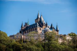 a castle on a hill with trees in the foreground at Superb - Schlossblick - Zentral - Smart TV in Wernigerode