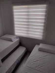 two twin beds in a room with a window at Buganviles 16, !Pura Vida! in Girardot