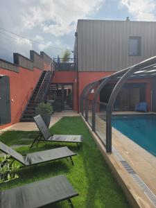 a building with a swimming pool and two lounge chairs at Villa Seyal - avec piscine - jacuzzi - sauna & climatisation in Le Mans