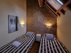 twee bedden in een kamer met een bakstenen muur bij Lovely Apartment in Mesch with Parking in Mesch