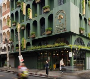 a green building with people walking in front of it at Cher Hostel Bangkok in Bangkok