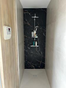 La salle de bains est pourvue d'un mur noir avec une croix sur une étagère. dans l'établissement Vakantie appartement Limburg, à Maaseik
