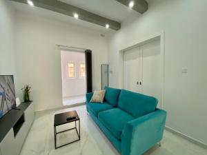 a living room with a blue couch and a table at Seaside Apartment in Gzira in Il-Gżira