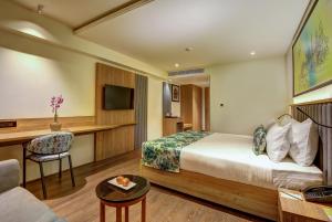 ein Hotelzimmer mit einem Bett und einem Schreibtisch in der Unterkunft Regenta Central Javaji Mysore in Mysore