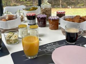 uma mesa coberta com copos de sumo de laranja e outros alimentos em Le Clos des Lilas em Graves