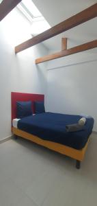 een bed in een witte kamer met blauwe en rode kussens bij Le 23 in Colombes