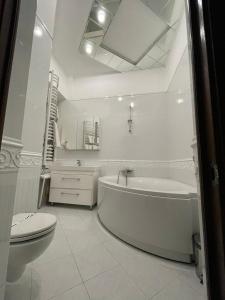 a white bathroom with a tub and a toilet at Prestige in Lviv