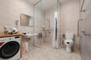 a bathroom with a shower toilet and a washing machine at Andros 4 All Seasons Villas & Suites in Andros