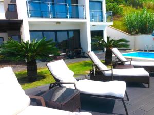 - un ensemble de chaises assises sur une terrasse à côté d'un bâtiment dans l'établissement Villa Alex,pool and ocean view, à Calheta
