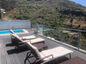 une terrasse avec deux chaises longues et une piscine dans l'établissement Villa Alex,pool and ocean view, à Calheta