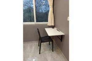 a table and chair in a room with a window at SAI 4BHK VILLA ALIBAUG in Alibaug