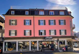 duży różowy budynek na rogu ulicy w obiekcie SCHNYDER'S HOME Studio_2 w mieście Rapperswil-Jona