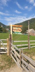 a wooden fence with a sign in a field at Casa Muchia lui Gîrniță in Braşov