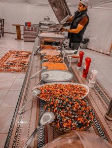 a man standing in a kitchen with a buffet of food at rum rema camp in Wadi Rum