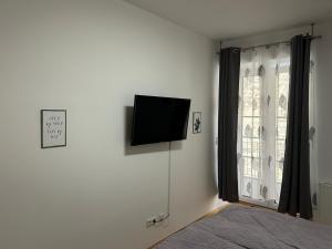1 dormitorio con TV en la pared junto a una ventana en Paky Appartements 00322 en Bruck an der Leitha