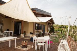 eine Terrasse mit weißen Tischen und Stühlen und ein Haus in der Unterkunft La Terrazza di Cirico' in Carlentini