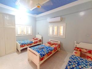 a room with two beds and two windows at Winji Guest house in Aswan