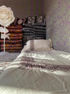 uma cama branca num quarto com uma pilha de cobertores em Bayzak guest house 