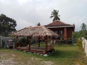 uma pequena cabana com um telhado de palha num quintal em Rumah Pantai Krui em Wainapal