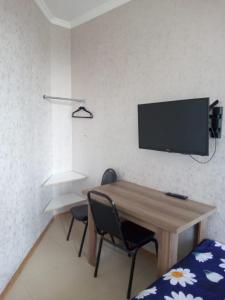 a room with a desk with two chairs and a tv on the wall at Gldani-house in Tbilisi City