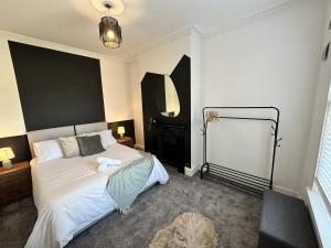 een slaapkamer met een groot wit bed met een zwart hoofdeinde bij 78 Victoria Road in Liverpool