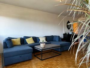 聖朱利安昂熱內瓦的住宿－Le Panorama，客厅配有一张蓝色的沙发,配有一张桌子