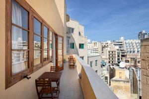 un balcone con sedie e tavoli su un edificio di Lapsi Apartments - Traditional Maltese Style near the Promenade a San Giuliano