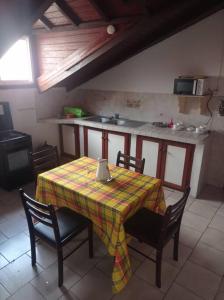 einen Tisch und Stühle in einer Küche mit einem Tisch und einer Tischdecke in der Unterkunft La Cour CoCoyer in Bouillante